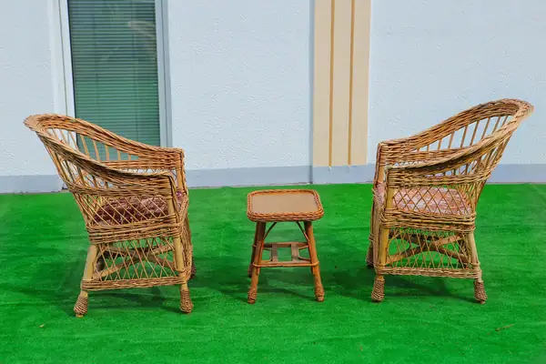 Wicker chairs and a small table on the lawn in front of the villa