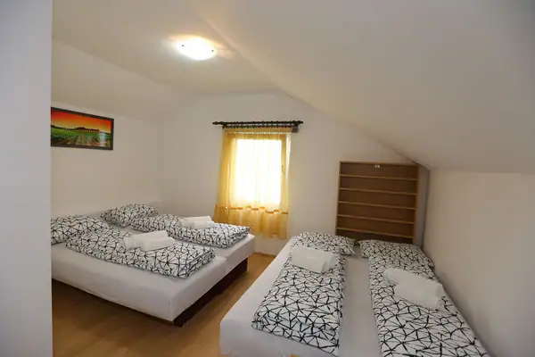 Attic bedroom with several beds and a window