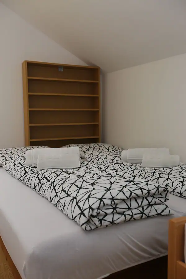 Bed with towels in front of a wooden shelf