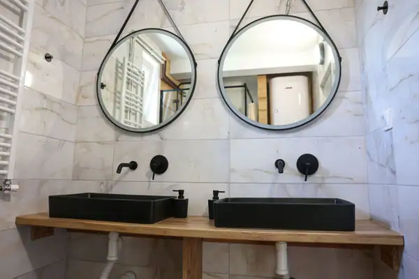 Two round mirrors and black basins